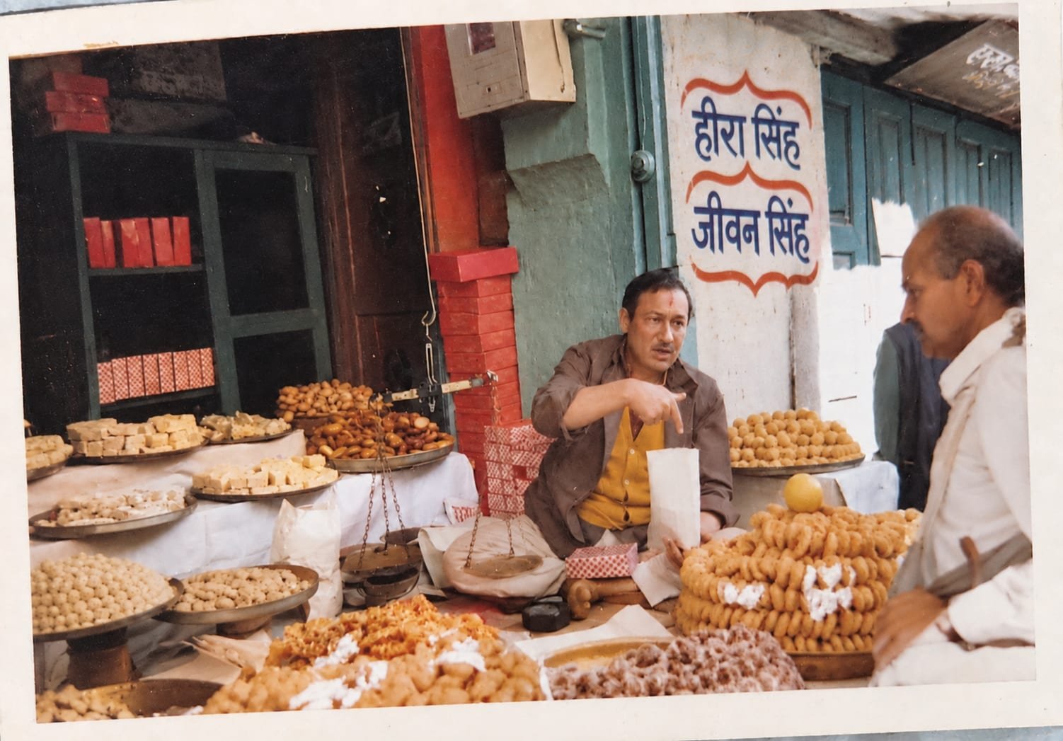 Archive photograph of a customer being served at the counter beneath the painted shop sign
