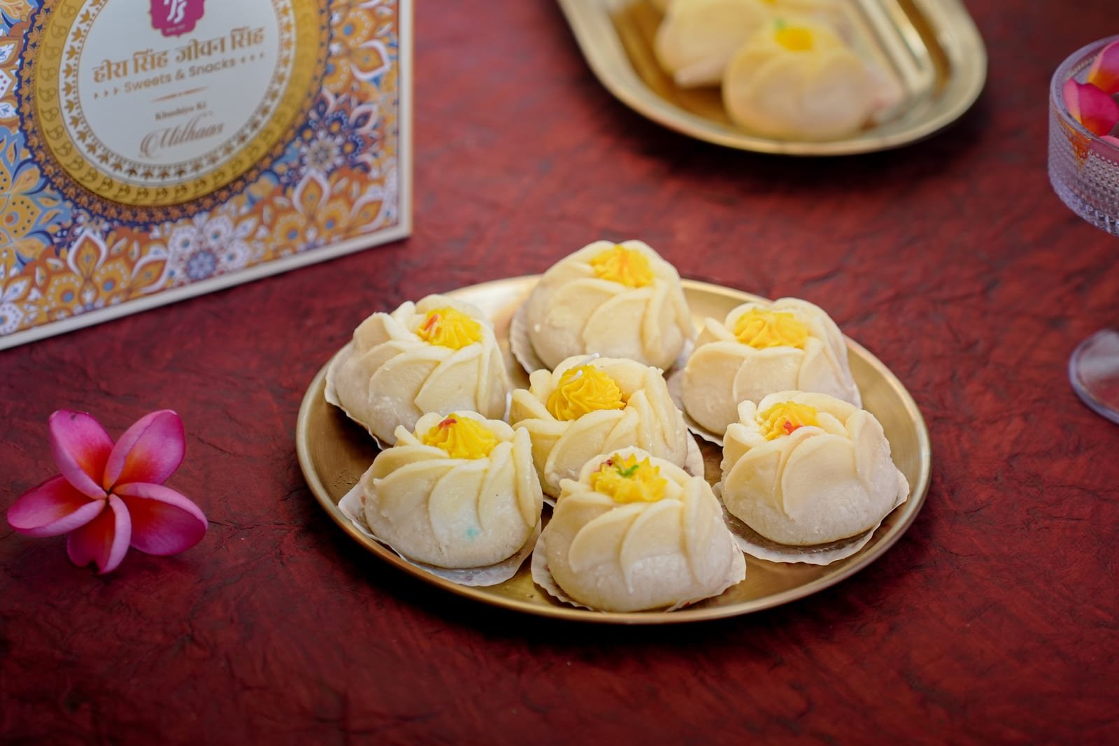 Anarkali sweets shaped like white flowers with saffron centres, on a gold plate