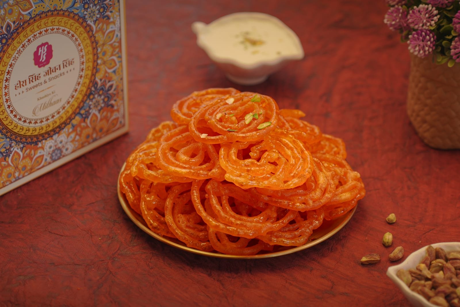 Bright orange jalebi coils stacked on a brass plate
