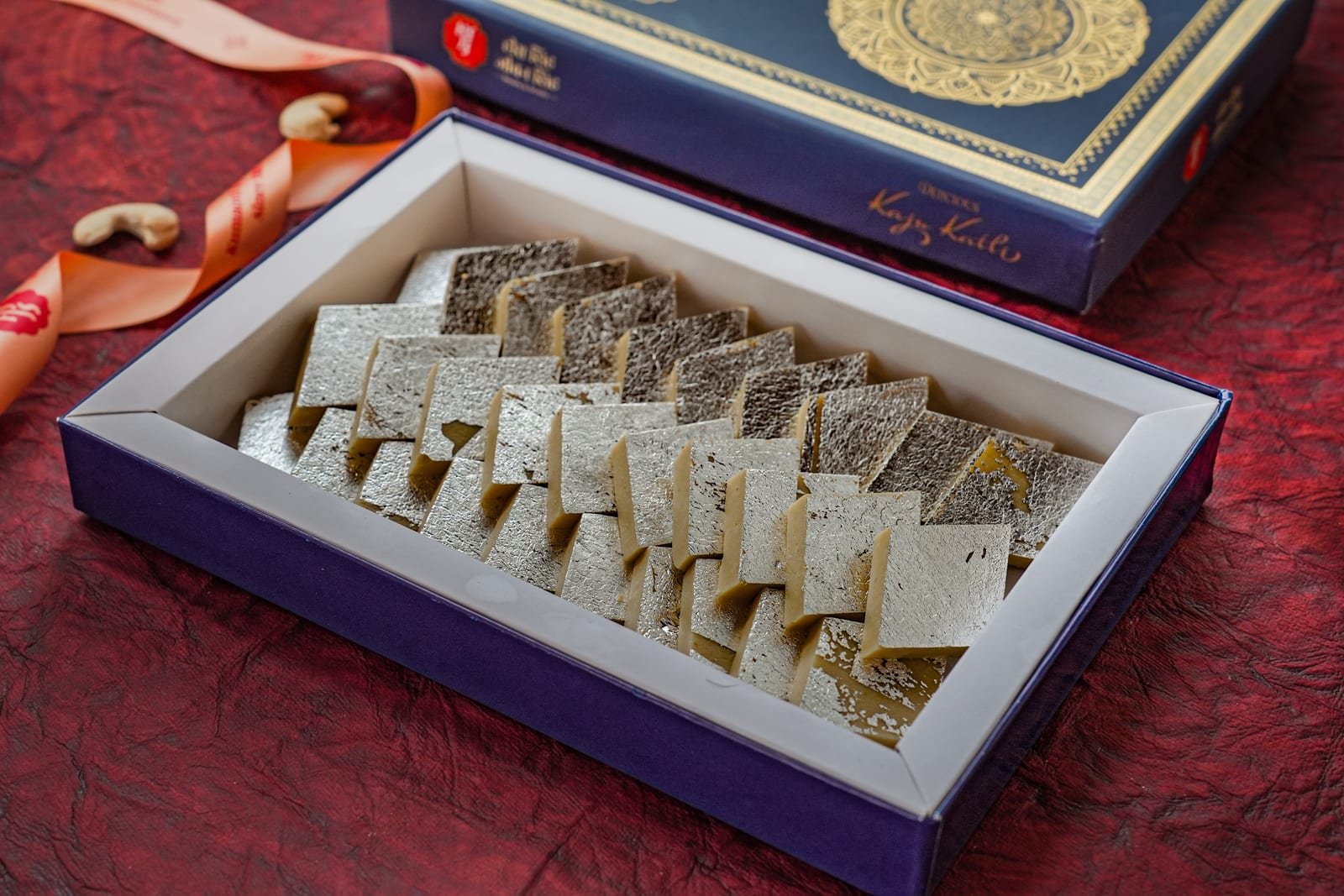 Rows of silver-leafed kaju katli diamonds packed into a gift box