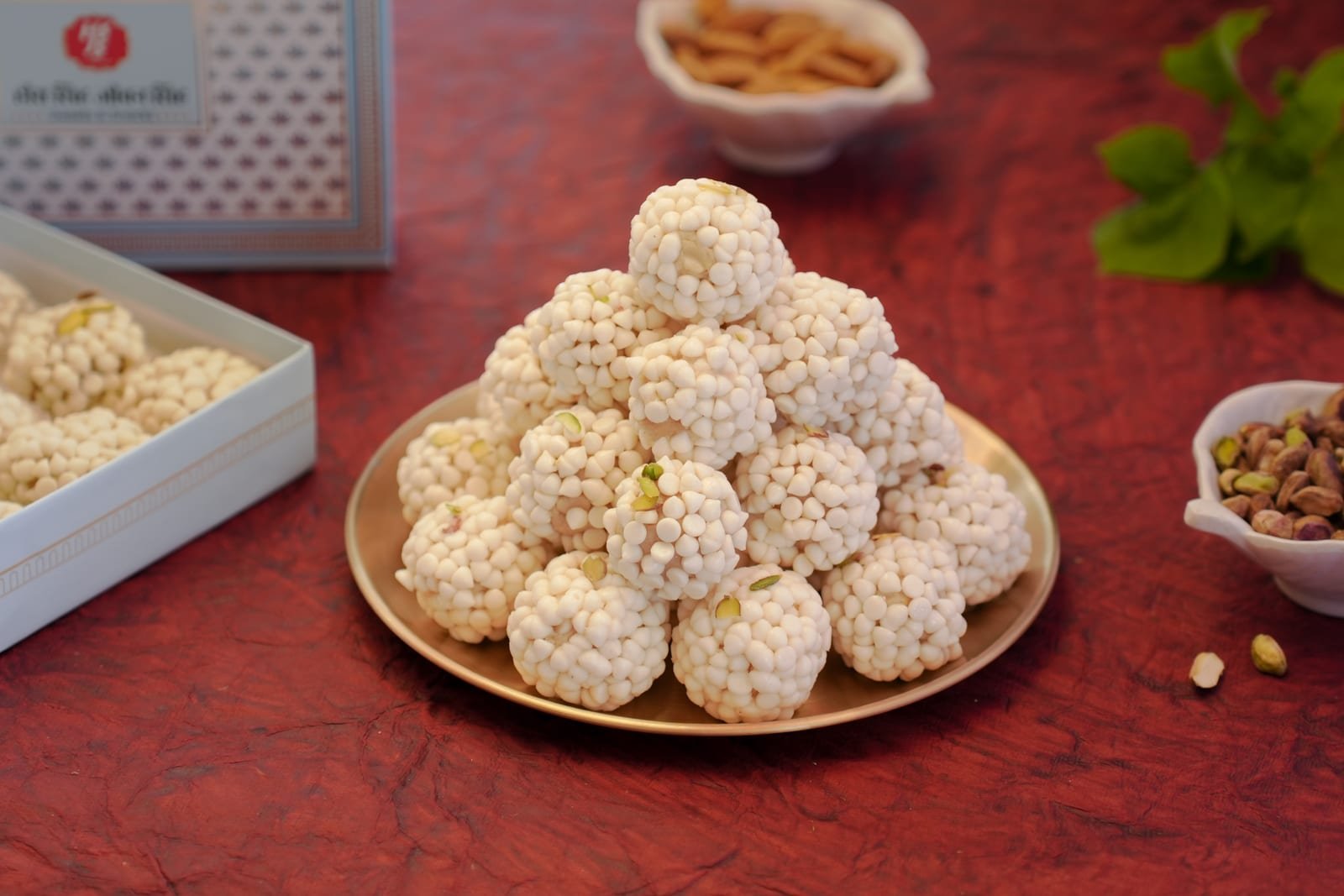 A pyramid of pearl-coated kaju laddu on a brass plate
