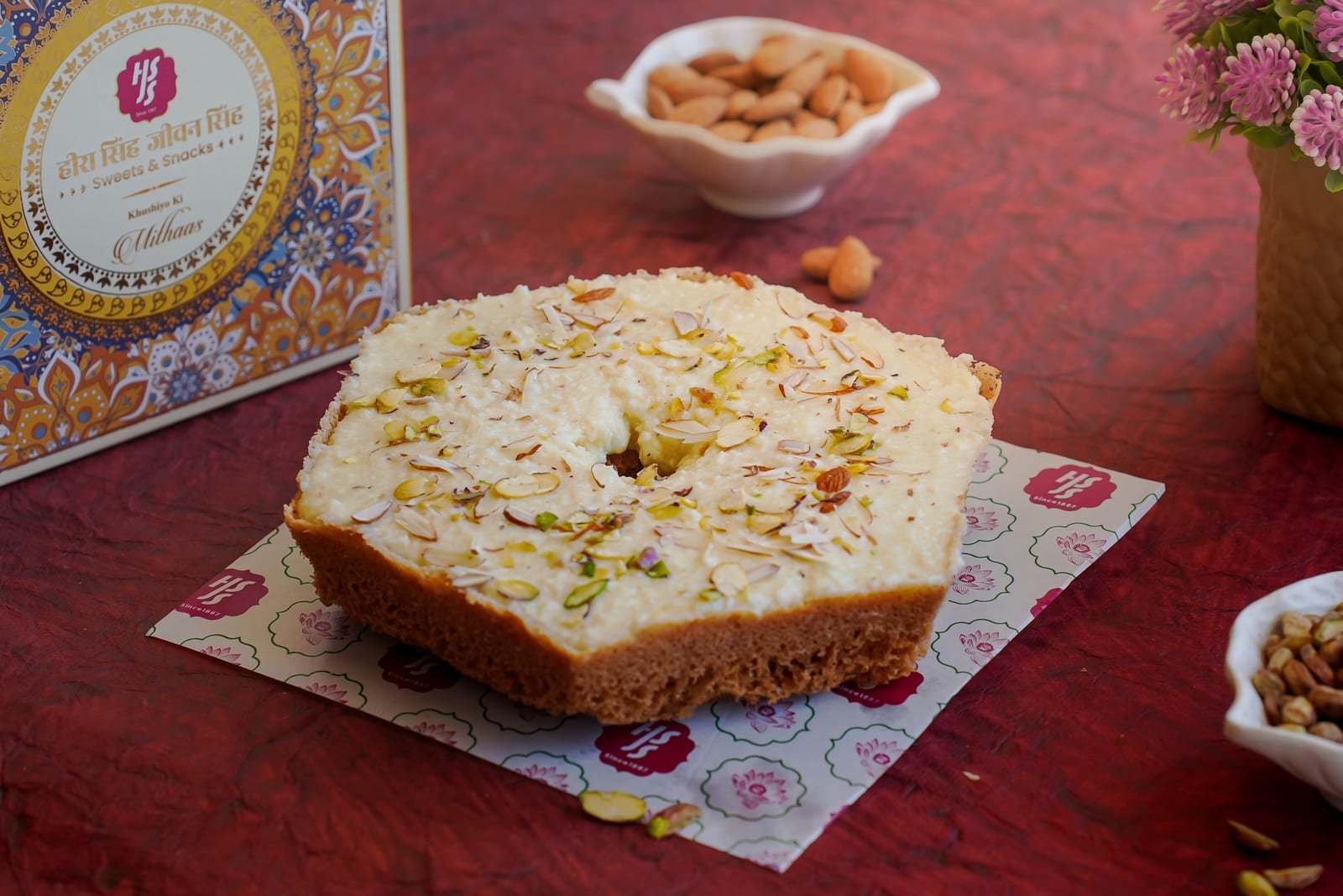 Malai ghewar on a brass plate, its lattice disc topped with cream, pistachio and silver leaf